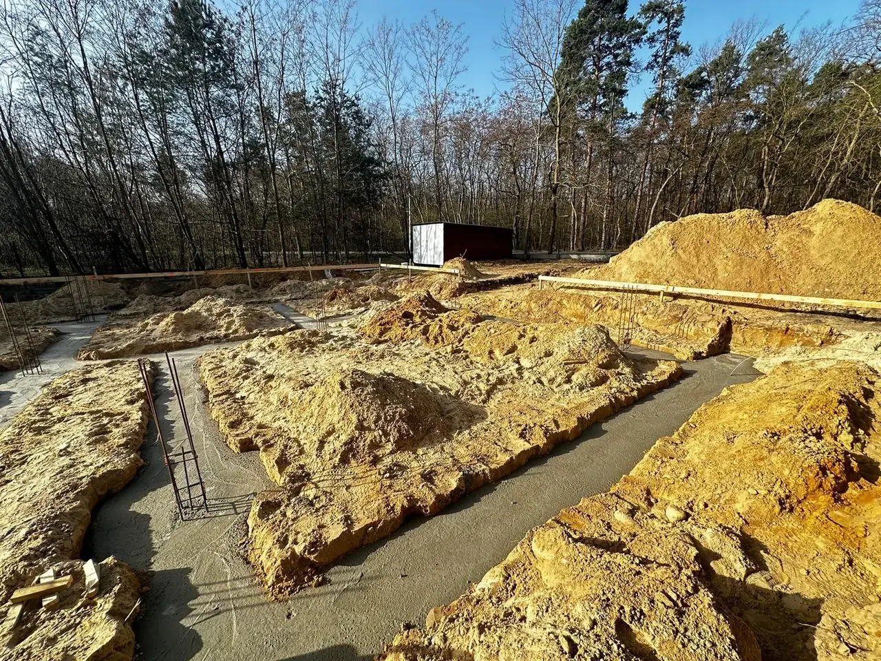 Świeżo zabetonowane ławy fundamentowe w wykopie
